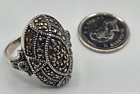 Close-up photo of the ring top showing detailed marcasite decoration and oval shape next to a coin for size reference.