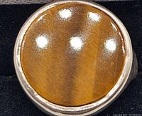 Close-up of the round tiger's eye stone set in a chunky silver bezel setting of the ring.