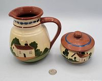 Photo of both vintage pottery pieces with quarter for scale. Pitcher with landscape motif beside lidded pot.