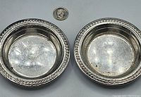 Two silver coasters shown from the top, revealing the beaded edge and concave well.