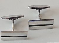 Pair of rectangular silver cufflinks showing front faces with horizontal black lines on a white background