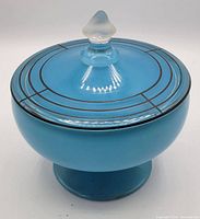 Closed view of the blue glass candy dish with lid on, showing black concentric line pattern and clear finial.