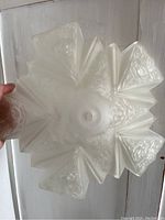 Overhead view of frosted glass shade showing star-shaped scalloped edges and embossed floral and geometric patterns.
