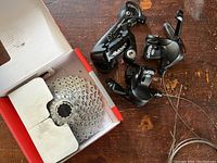 Shimano Deore derailleur and shifters with cables beside a box containing the SRAM cassette.