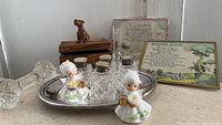Overview photo showing tray, crystal shakers with silver pearl tops, wooden box with Scottie dog lid, two vintage motto prints, two Napco angel candle holders, and dumbbell shaped crystal knife rests.