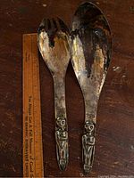 Pair of silver plated servers, a spoon and a fork, showing full length with a ruler for scale on wood surface.