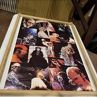 Photo showing collage poster with multiple images of Elton John in 1970s stage costumes and eyeglasses, laid flat on a surface with original storage sleeve edges visible.