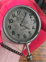 Front view of antique Elgin 8 days automobile clock showing numbered dial with dirt and wear