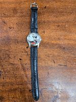 Front view of the Disney Mickey Mouse wristwatch showing the round face with Mickey Mouse image and black leather strap.