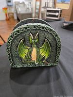 Front view of decorative dragon napkin or mail holder showing green dragon with wings on textured circular holder with Celtic border.