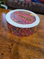 Closed storage box covered with kaleidoscope design paper, showing embossed white rim on lid