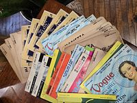 Lot of vintage hairnets in original packaging showing various brands and colors spread on table.