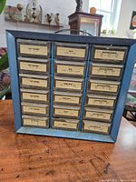 Front view of metal mini drawer cabinet with 24 labeled small drawers for organizing screws and hardware parts.