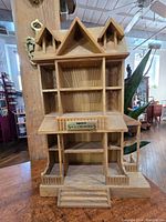 Front view of Enesco Small Wonders vintage wooden display showing peaked roof dollhouse design with multiple shelves and front porch with stairs