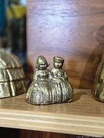 Front view of vintage brass bell figurine showing Dutch girl and boy in traditional dress.