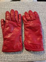 Top side view of pair of red leather gloves showing overall condition and color.