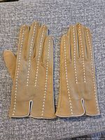 Full view of both camel leather gloves laid flat with white stitching.