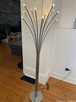 Full view of the Ikea LED floor lamp showing its multiple curved metal arms spreading from a round base and illuminated tips.