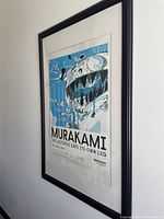 Framed poster showing a blue octopus creature and human characters from Murakami exhibit.