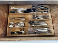 Drawer with organized flatware including forks, spoons, knives, butter knives