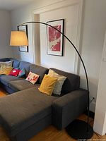 Full view of black arc floor lamp positioned over couch, showing overall design and placement