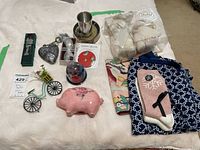Lot overview showing all items including Bearington Baby security blanket and plush set, ceramic piggy bank, Nautica pants, pewter cup, decorative items, and socks.