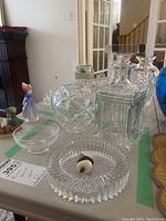 Mixed glassware including the Birks decanter, ashtray, figurines and bowls arranged on table.