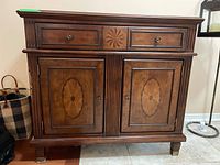 Front view of wood cabinet showing drawer and two-panel lower doors with inlay