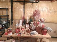 Overview of the Christmas decorations on wooden table including faux florals, multiple small trees, ornaments, and pinecones.
