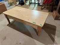 Rectangular light wood coffee table from a side angle showing top surface and legs, set in a basement area.