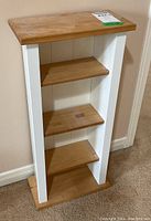 Angle view of the wood display shelf showing three adjustable natural wood shelves within white painted frame.