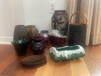 Wide view of all vases including glass, ceramic, and metal pieces on wood floor