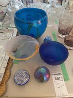 Overview of the art glass collection arranged together showing various bowls, vase, and paperweights on a table.
