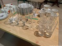 Table set with six etched tumblers showing floral patterns, grouped with eight champagne flutes in two styles: four with smooth stems and four with ornate stems.