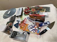 Photo of various packaged and loose kitchen tools and accessories laid out on a white surface.