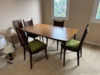 Room view shows rectangular wood table with three leaves installed and four matching chairs with green seats