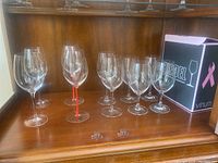 Group of seven wine glasses in wooden cabinet: two Rosenthal clear-stem, one Riedel red-stem, five Riedel clear-stem