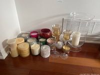 Wide shot showing all candles and candle holders including glass vase, colored glass container candles, and metallic holders.