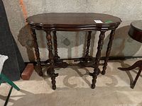 Wood side table with detailed carving, turned legs, and visible marks, photographed from an angle showing front and side.