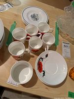 Overview of all cups, saucers, and plates on a wooden table showing the Cornpoppy red floral pattern