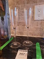 Two clear Tiffany & Co stemware glasses with long stems and circular bases on a countertop.