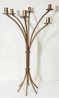 Front view of vintage freestanding wrought iron candle holder showing curved design and brass tone.