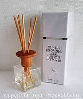 Clear glass diffuser bottle with light brown reeds next to a white rectangular box labeled Omnibus Fragrance, Scent: Tuberose, 30 ml.