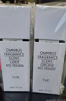 Photo shows two Omnibus fragrance diffuser boxes, one with Linen scent for Sun, and one with Orchid scent for Tue, both sealed in plastic.