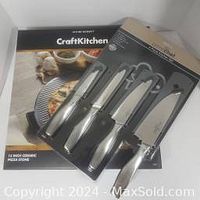 Box and partial view of the 4-piece Prime Chef cutting tool set including knives and peeler with covers.