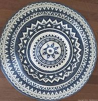 Top view of round cotton rug displaying detailed blue and white mandala pattern on wooden floor.