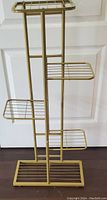 Front and side views of the vintage gold tone metal plant stand showing three staggered shelves and a rectangular base.