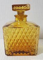 Front view of vintage amber glass decanter showing diamond cut pattern and squared stopper.
