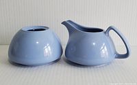 Side view of powder blue ceramic creamer and sugar bowl showing smooth finish and shape.