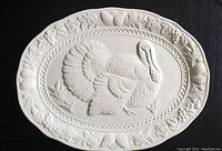 Top view of the entire white ceramic oval platter showing raised turkey in center and floral border pattern.